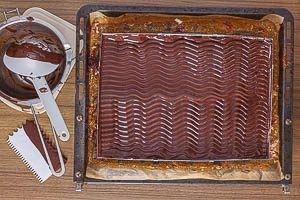 Kuvert&uuml;re-Glasur auf der Buttercreme verstreichen und ein Wellenmuster ziehen
