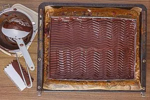 Kuvert&uuml;re-Glasur auf der Buttercreme verstreichen und ein Wellenmuster ziehen