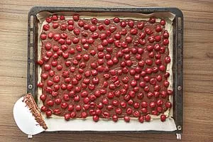 Abgetropfte Kirschen auf dem dunklen Teig verteilen