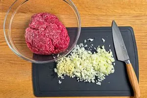 Zwiebeln klein hacken und Hackfleisch in die Sch&uuml;ssel geben.