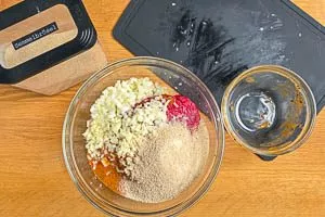 Die Fl&uuml;ssige W&uuml;rze mit Zwiebeln, Knoblauch und Paniermehl mit dem Hackfleisch vermengen.