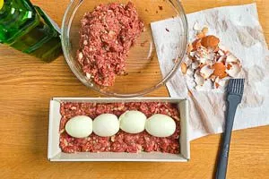 Hackmasse und Eier in die Form geben.