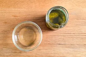Gurkenwasser in eine Sch&uuml;ssel abf&uuml;llen