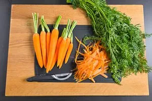 Das Gr&uuml;n der M&ouml;hren abschneiden, Karotten waschen und sch&auml;len