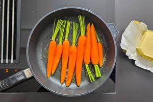 Butter in einer Pfanne erhitzen und Möhren kurz anbraten
