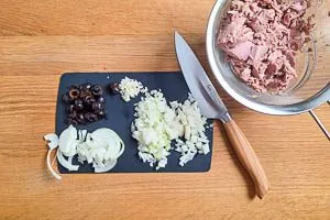 Thunfisch abtropfen lassen und mit einer Gabel zerkleinern, Knoblauch und Zwiebeln w&uuml;rfeln und Oliven in Scheiben schneiden