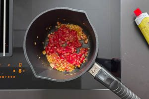 Tomatenmark zu den Zwiebeln und dem Knoblauch geben