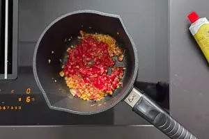 Tomatenmark zu den Zwiebeln und dem Knoblauch geben