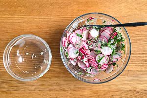 Dressing mit Radieschen und Petersilie vermengen