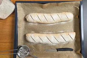 Baguette-Teigstr&auml;nge mit Mehl best&auml;uben und schr&auml;g einschneiden