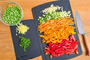 Knoblauch, Ingwer, Peperoni und Gem&uuml;se kleinschneiden