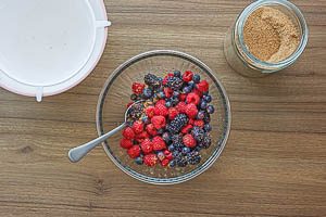 Abgetropfte frische Beeren mit braunem Zucker vermischen