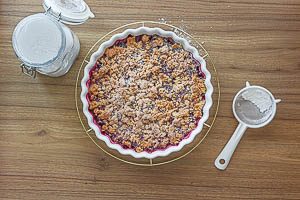 Gebackenen Beeren-Crumble mit Puderzucker bestreuen