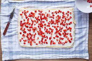 Biskuitteig mit Creme und Erdbeeren bestreichen