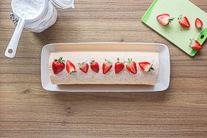 Mit Puderzucker bestreuen und Erdbeeren garnieren