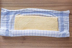 Biskuitboden mit K&uuml;chentuch aufrollen.