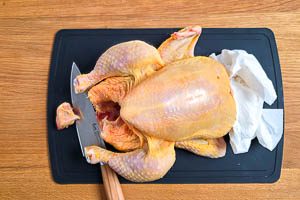 H&auml;hnchen abtupfen, B&uuml;rzel abschneiden, Fl&uuml;gel verschr&auml;nken und Fl&uuml;gelspitze &uuml;ber den Unterarm