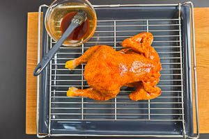 H&auml;hnchen auf ein Rost und darunter ein Backblech, mit Marinade bestreichen