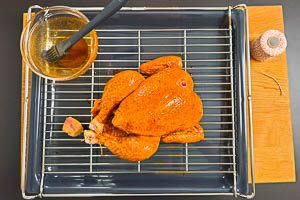 H&auml;hnchen drehen, Beine zusammenbinden und mit Marinade bestreichen und in den Ofen schieben