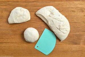 Pizzateig in vier St&uuml;cke teilen und zu Kugeln formen