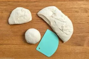 Pizzateig in vier St&uuml;cke teilen und zu Kugeln formen