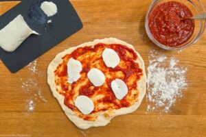 Tomatensugo auf Pizzen verteilen und mit Mozzarella belegen