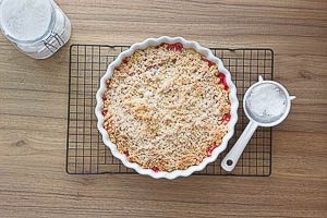 Puderzucker auf den gebackenen Rhabarber-Crumble streuen