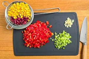 Fr&uuml;hlingszwiebeln, Knoblauch und Paprikaschote schneiden, Kidneybohnen und Mais abtropfen lassen