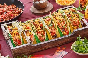 Vegetarische Tacos mit Eisbergsalat und der Sojaf&uuml;llung bef&uuml;llen und mit K&auml;se bestreuen