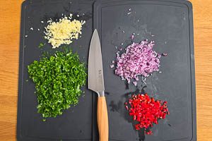 Petersilie waschen, trocknen und schneiden, rote Zwiebeln und Knoblauch sch&auml;len und fein w&uuml;rfeln, rote Peperoni fein w&uuml;rfeln