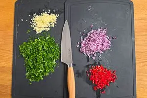 Petersilie waschen, trocknen und schneiden, rote Zwiebeln und Knoblauch sch&auml;len und fein w&uuml;rfeln, rote Peperoni fein w&uuml;rfeln