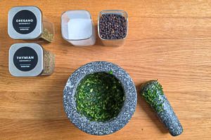 Petersilie, Oregano, Thymian, Meersalz, Pfefferk&ouml;rner und Knoblauch im M&ouml;rser zersto&szlig;en