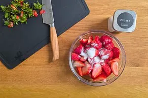 Erdbeeren waschen, schneiden und mit Zucker vermischen