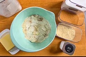 Mehl, gemahlene Mandeln, kalte Butter, weißer und brauner Zucker und etwas Salz für Streusel vermengen