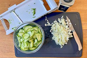 Zwiebel schälen und würfeln, Gurke waschen, schälen und hobeln, mit Salz bestreuen und entwässern lassen