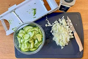Zwiebel sch&auml;len und w&uuml;rfeln, Gurke waschen, sch&auml;len und hobeln, mit Salz bestreuen und entw&auml;ssern lassen