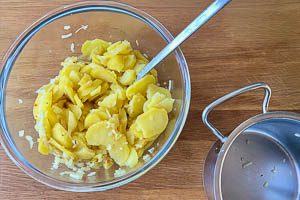 Dressing mit Kartoffelscheiben vermischen
