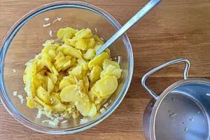 Dressing mit Kartoffelscheiben vermischen