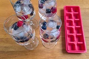 Beeren, Eiswürfel und Minze ins Glas geben