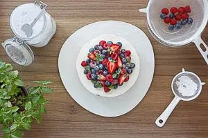 Nach dem K&uuml;hlen mit Puderzucker best&auml;uben und die restlichen Beeren auf dem Kuchen verteilen