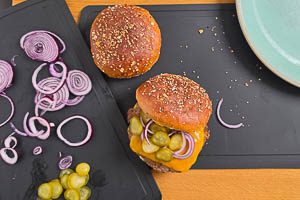 Patties mit Käse auf die untere Hälfte legen, mit Gewürzgurken und Zwiebeln belegen und dann mit der oberen Hälfte schließen