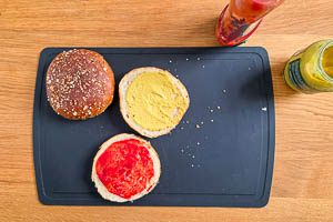Buns erwärmen, zerschneiden, eine Seite mit Ketchup und eine Seite mit Senf bestreichen