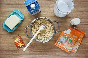 Für das Topping Butter, Zucker, Bourbon-Vanillezucker, Salz und Milch im Kochtopf köcheln lassen und die Mandelblättchen dazugeben