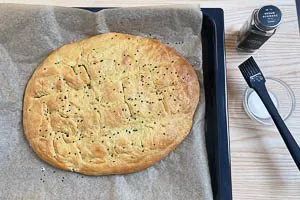 Nach dem Backen Milch auf das Fladenbrot pinseln und es mit Sesam bestreuen