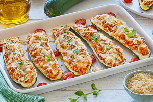 &Uuml;berbackene vegetarisch gef&uuml;llte Zucchini frisch aus dem Ofen holen und warm servieren