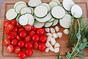 Zucchini, Kirschtomaten und Knoblauch schneiden