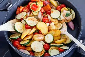 Tomaten, Zucchini und Knoblauch hinzugeben und w&uuml;rzen