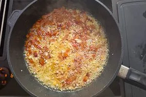 Zwiebel- und Knoblauchwürfel in die Pfanne geben