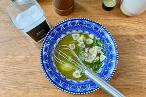 Restliche Zutaten für die Marinade in die Schüssel geben: Olivenöl, Zitronensaft und -abrieb, Minze, Salz, Pfeffer und Zucker