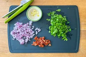 Zwiebel, Knoblauch, getrocknete Tomaten und Petersilie vorbereiten.